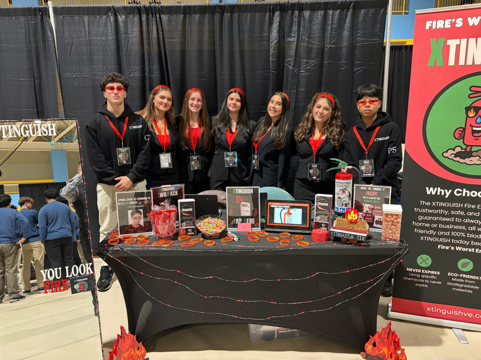  Xtinguish's tradeshow table. (L to R: CTO Robbie Cambell, COO Alexandra Boeckmann, CFO Madyn Kalb, CEO Leila O'Toole, CSO Ella Palatnek, CMO Eva Richter, Caleb Lee)  
